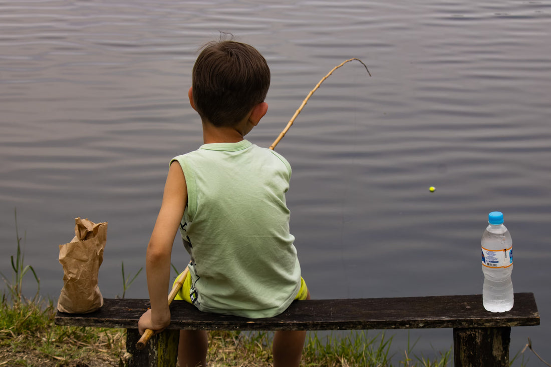 Boy Fishing While Sitting on a Bench